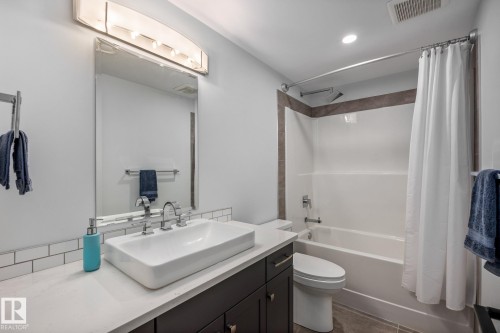 Bathroom featuring a contemporary vessel sink, white countertop, dark wood-finish vanity, subway tile backsplash, and a shower/tub combination with tiled surround - 14221 101 Avenue Nw, Edmonton, AB - Indoor Photo Showing Bathroom