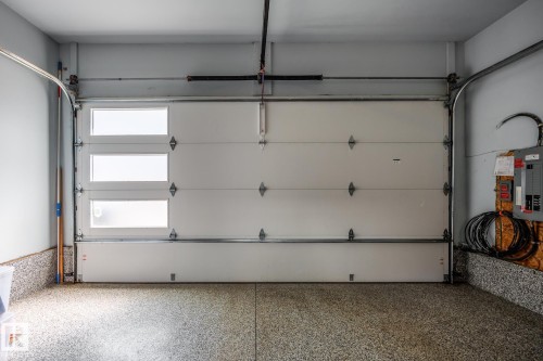 Garage interior featuring a contemporary white overhead door with three horizontal frosted glass panels - 14221 101 Avenue Nw, Edmonton, AB - Indoor Photo Showing Garage