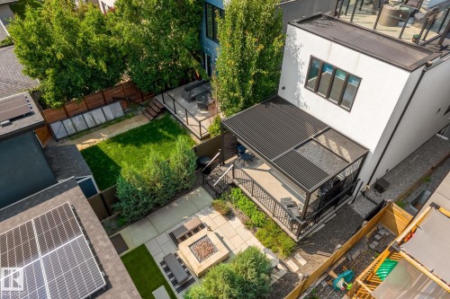 Expansive multi-level backyard featuring a covered deck, stone patio with built-in fire pit, manicured lawn, and mature trees - 14221 101 Avenue Nw, Edmonton, AB - Outdoor