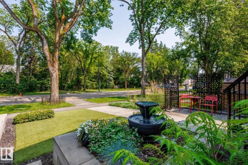 Front yard featuring a tiered water fountain, landscaping with varied plantings, and a manicured lawn section - 14221 101 Avenue Nw, Edmonton, AB - Outdoor