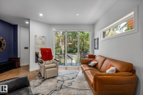 Bright living space featuring light wood-finish flooring, recessed lighting, and a large glass sliding door opening to exterior steps - 14221 101 Avenue Nw, Edmonton, AB - Indoor Photo Showing Living Room