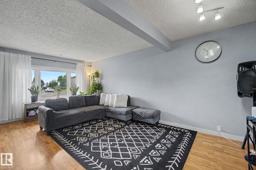 Living room featuring wood-finish flooring, a large picture window, and a textured ceiling - 18407 95A Avenue Nw, Edmonton, AB - Indoor Photo Showing Living Room