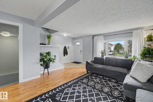 Open-concept living area featuring wood-finish flooring, a large bay window, and light grey wall tones - 18407 95A Avenue Nw, Edmonton, AB - Indoor Photo Showing Living Room