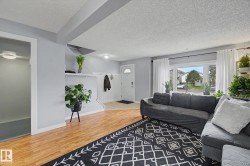 Open-concept living area featuring wood-finish flooring, a large bay window, and light grey wall tones - 