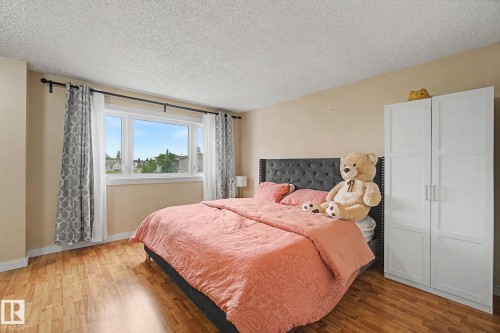 Bedroom featuring wood-finish flooring, a multi-pane window with a white frame, and a white built-in wardrobe with panel detailing and silver hardware - 18407 95A Avenue Nw, Edmonton, AB - Indoor Photo Showing Bedroom