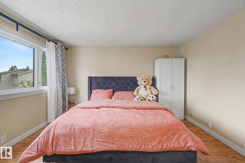 Bright room featuring a large window, light-toned walls, wood-finish flooring, and a white built-in storage unit - 18407 95A Avenue Nw, Edmonton, AB - Indoor Photo Showing Bedroom