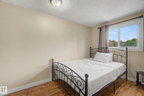 Room featuring wood-finish flooring, a window with white trim, and a ceiling-mounted light fixture - 18407 95A Avenue Nw, Edmonton, AB - Indoor Photo Showing Bedroom