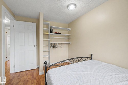 Room featuring wood-finish flooring, a white paneled door, and a built-in shelving system with hanging rod - 18407 95A Avenue Nw, Edmonton, AB - Indoor Photo Showing Bedroom