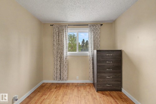 Bright room featuring a window with patterned drapes, wood-finish flooring, and light-toned walls - 18407 95A Avenue Nw, Edmonton, AB - Indoor Photo Showing Other Room