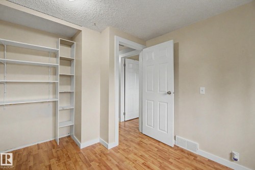 Room featuring built-in shelving, wood-finish flooring, light neutral wall paint, and white trim - 18407 95A Avenue Nw, Edmonton, AB - Indoor