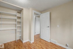 Room featuring built-in shelving, wood-finish flooring, light neutral wall paint, and white trim - 