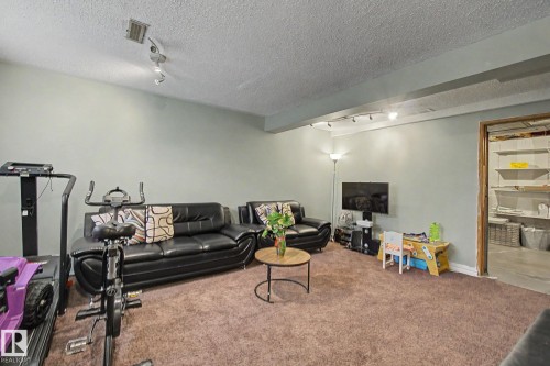 Spacious room featuring textured ceiling, light grey walls, brown carpet flooring, and track lighting - 18407 95A Avenue Nw, Edmonton, AB - Indoor Photo Showing Other Room