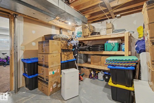 Unfinished basement storage area featuring exposed wood ceiling joists and ductwork, a concrete floor, and built-in wood shelving - 18407 95A Avenue Nw, Edmonton, AB - Indoor Photo Showing Basement