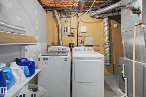 Dedicated utility area featuring washer and dryer units, exposed ceiling joists, and a visible electrical panel - 18407 95A Avenue Nw, Edmonton, AB - Indoor