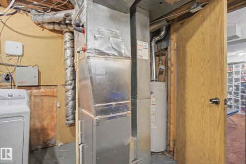 Furnace and water heater system with exposed ductwork and utility connections - 18407 95A Avenue Nw, Edmonton, AB - Indoor Photo Showing Basement