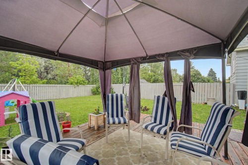 Expansive backyard featuring a gazebo-covered deck with privacy curtains, a manicured lawn, and a light-toned privacy fence - 18407 95A Avenue Nw, Edmonton, AB - Outdoor With Deck Patio Veranda With Exterior