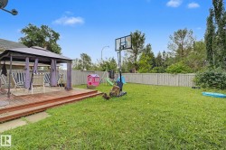Expansive backyard featuring a multi-level wooden deck with a covered gazebo, a large grassy area, privacy fencing, and mature perimeter foliage - 