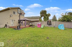 Spacious rear yard with a wooden privacy fence, expansive lawn area, and a raised wooden deck - 