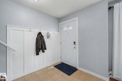 Entryway featuring a white board and batten wall with integrated hooks, light-toned tile flooring, and a white entry door with an arched glass insert - 