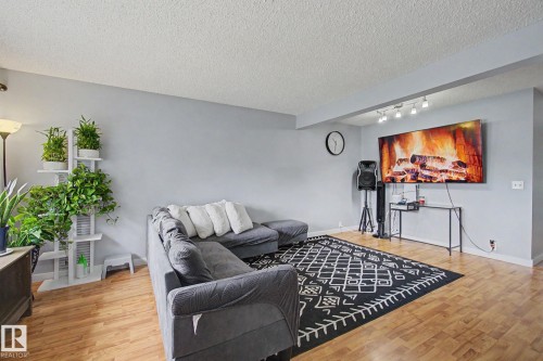 Living area featuring light wood-finish flooring, light gray wall paint, and a textured white ceiling - 18407 95A Avenue Nw, Edmonton, AB - Indoor