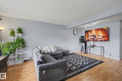 Living area featuring light wood-finish flooring, light gray wall paint, and a textured white ceiling - 