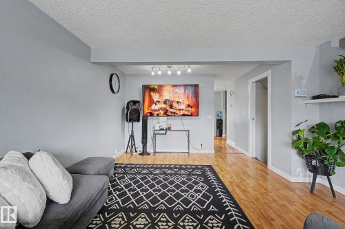 Open-concept living space with light gray walls, wood-finish flooring, and a recessed ceiling beam - 18407 95A Avenue Nw, Edmonton, AB - Indoor