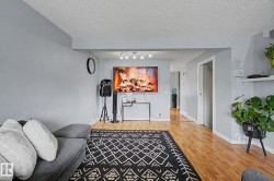 Open-concept living space with light gray walls, wood-finish flooring, and a recessed ceiling beam - 