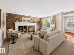 Living area featuring a stone accent wall, white mantel fireplace with built-in shelving, large windows with white trim, recessed lighting, and carpeting - 