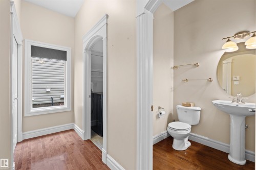 Bathroom featuring a pedestal sink, round mirror, and a wall-mounted light fixture - 1338 Rutherford Road Sw, Edmonton, AB - Indoor Photo Showing Bathroom