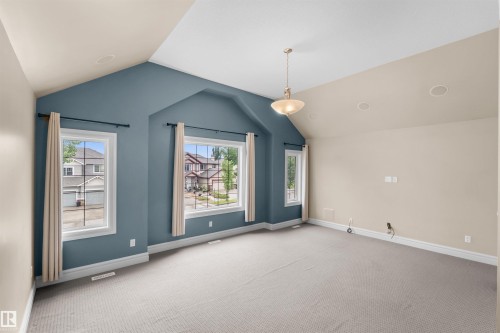 Spacious room featuring vaulted ceilings, a central pendant light fixture, recessed ceiling speakers, light gray carpeting, and multiple windows with white trim - 1338 Rutherford Road Sw, Edmonton, AB - Indoor Photo Showing Other Room