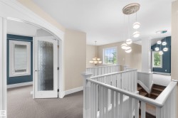 Upper-level landing featuring a white spindle railing system, light neutral wall paint, and multiple pendant light fixtures - 