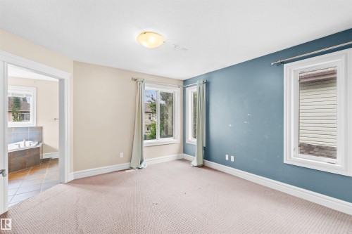 Carpeted room featuring multiple windows with white trim, a semi-flush mount ceiling light, and a two-tone wall treatment - 1338 Rutherford Road Sw, Edmonton, AB - Indoor