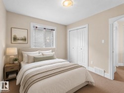Carpeted bedroom featuring a window with blinds, a ceiling-mounted light fixture, white trim, and a bi-fold closet door - 