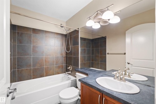 Bathroom featuring a vanity with a single basin, dark countertop, and wood-finish cabinetry - 1338 Rutherford Road Sw, Edmonton, AB - Indoor Photo Showing Bathroom