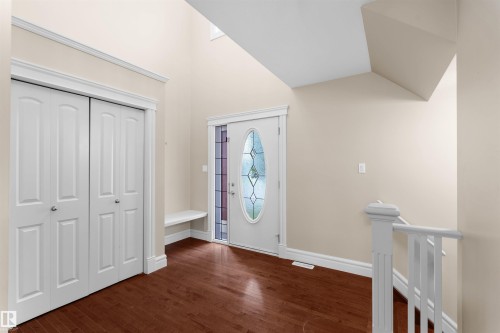 Entryway featuring rich wood-finish flooring, a decorative glass-paneled entry door, a built-in bench, and a coat closet with bi-fold doors - 1338 Rutherford Road Sw, Edmonton, AB - Indoor Photo Showing Other Room