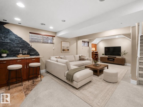 Finished lower level featuring recessed lighting, a built-in wet bar with stone-look countertop and wood cabinetry, and a stone accent wall - 1338 Rutherford Road Sw, Edmonton, AB - Indoor Photo Showing Other Room