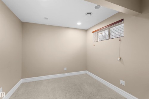 Room featuring neutral wall paint, light-colored carpeting, white baseboards, and a window with wood-finish blinds - 1338 Rutherford Road Sw, Edmonton, AB - Indoor Photo Showing Other Room