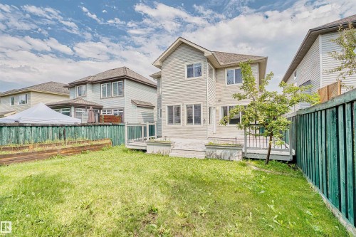 Rear exterior featuring light-colored siding, multiple windows, and a multi-level wood-finish deck - 1338 Rutherford Road Sw, Edmonton, AB - Outdoor With Deck Patio Veranda
