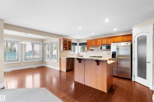 Kitchen featuring wood-finish flooring, stainless steel appliances, a kitchen island with stone countertop, wood cabinetry, and recessed lighting - 1338 Rutherford Road Sw, Edmonton, AB - Indoor Photo Showing Kitchen