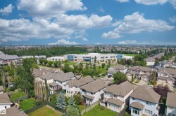 Aerial perspective showcasing a residential neighborhood with detached homes, mature trees, and a distant institutional building with a blue facade - 