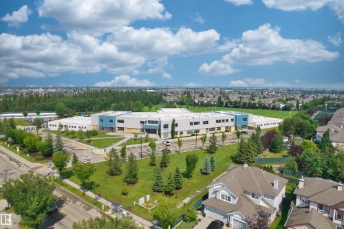Expansive neighborhood featuring a large institutional building with modern blue and grey accents, extensive green spaces, and surrounding residential properties - 1338 Rutherford Road Sw, Edmonton, AB - Outdoor With View
