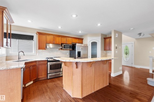 Kitchen featuring wood cabinetry, stainless steel appliances, light-toned countertops, and wood-finish flooring - 1338 Rutherford Road Sw, Edmonton, AB - Indoor Photo Showing Kitchen With Upgraded Kitchen