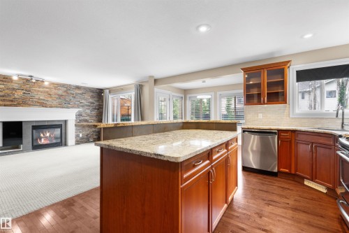 Kitchen island with granite countertop and wood-finish cabinetry - 1338 Rutherford Road Sw, Edmonton, AB - Indoor Photo Showing Kitchen With Fireplace