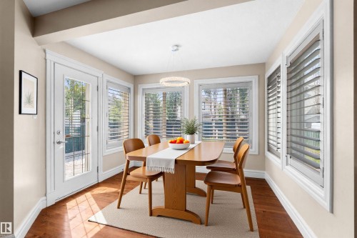 Dining area featuring multiple windows with louvered blinds, a glass-paned door, and wood-finish flooring - 1338 Rutherford Road Sw, Edmonton, AB - Indoor Photo Showing Dining Room