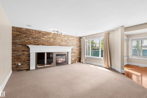Living space featuring a stacked stone accent wall with a white mantel and gas fireplace - 1338 Rutherford Road Sw, Edmonton, AB - Indoor Photo Showing Other Room With Fireplace