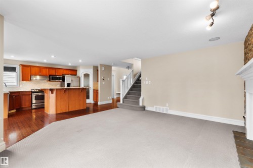 Open-concept living area featuring a kitchen with wood cabinetry, stainless steel appliances, and a central island with bar seating - 1338 Rutherford Road Sw, Edmonton, AB - Indoor Photo Showing Kitchen