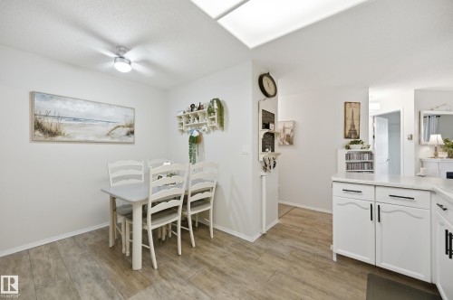 Open-concept living space featuring wood-finish flooring, white cabinetry with black hardware, and a skylight - #208 9760 176 St Nw, Edmonton, AB - Indoor Photo Showing Dining Room