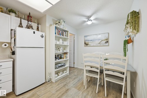 Dining area featuring wood-finish flooring, a built-in shelving unit, and a ceiling-mounted light fixture - #208 9760 176 St Nw, Edmonton, AB - Indoor