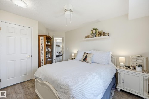 Bright room featuring wood-finish flooring, a six-panel door, and a ceiling fan with integrated lighting - #208 9760 176 St Nw, Edmonton, AB - Indoor Photo Showing Bedroom