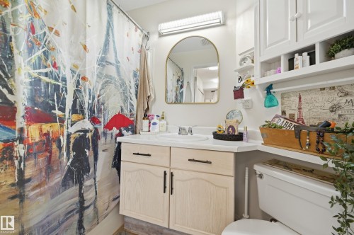 Bathroom featuring a light-toned vanity with cabinet storage, white countertop, and a single sink - #208 9760 176 St Nw, Edmonton, AB - Indoor Photo Showing Bathroom